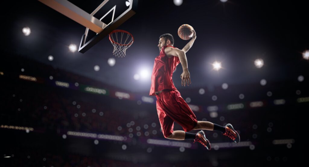 Basketball player jumping through the air to slam the ball through hoop