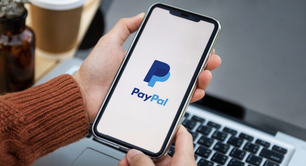 Person holding a smartphone with PayPal logo on screen